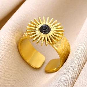 Macro shot of gold sunburst ring featuring a central black gemstone on textured fabric