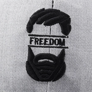 Detailed close-up of Freedom letter embroidery on gray cotton baseball cap fabric