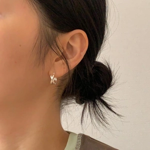 Close-up of minimalist crossover silver earrings on model showcasing a refined daily style