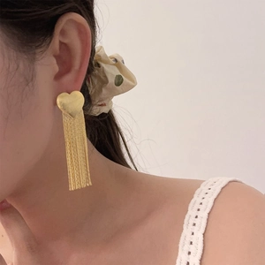 Elegant gold heart long tassel earrings worn by a model against a neutral background