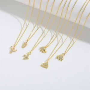 Detail of gold pendant necklaces featuring elephant, owl, and bull charms with zircon stones