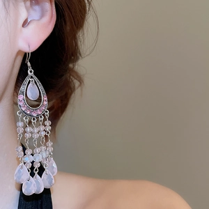 Close-up of pink crystal tassel earrings with teardrop beads worn by a model