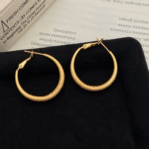 Detail of gold hoop earrings with sparkling frosted texture and polished inner finish