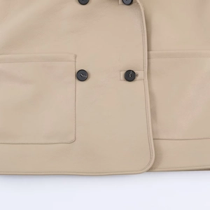 Close-up of beige leather jacket with black buttons and detailed stitching textures
