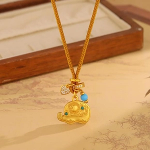Detail of a gold necklace featuring an elephant pendant, heart charm, and blue bead