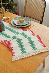 Detail of Christmas table runner featuring woven trees, red triangles, and tassels