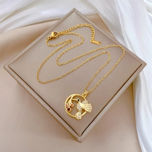 Detail of gold titanium hummingbird pendant with pavé white crystals on a jewelry box