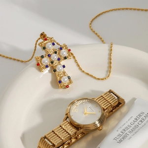 Collana con croce dorata con gemme e perle abbinata a un orologio di lusso