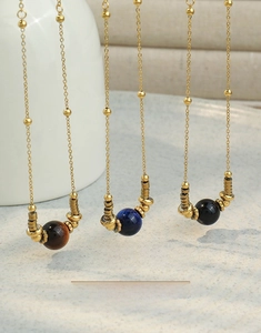 Détail des colliers en acier titane avec pendentifs œil de tigre et lapis-lazuli