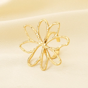 Close-up of golden hollow flower ring on cream silk background for a minimalist style
