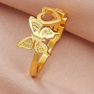 Close-up of gold butterfly and heart adjustable ring on pink silk fabric background