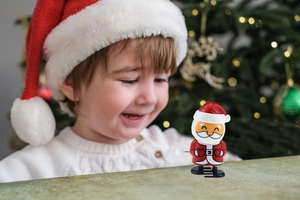 Père Noël mécanique marchant sur une table en bois avec un enfant joyeux en arrière-plan