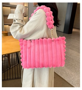 Pink plush tote bag with vertical stripes and fluffy ball shoulder strap on a model