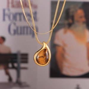 Gold double-layered necklace featuring a teardrop tiger eye pendant and sleek snake chain