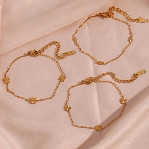 Set of three 18K gold plated stainless steel bracelets with flower and geometric pendants