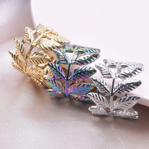 Detailed macro view of retro leaf rings in gold, silver, and rainbow steel finishes