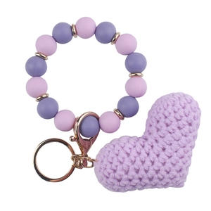 Detail of purple silicone beaded bracelet with knitted heart pendant and golden keyring