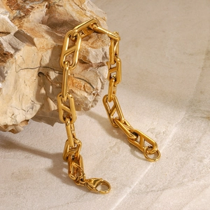 Detail of a chunky gold stainless steel chain bracelet hanging on a natural rock