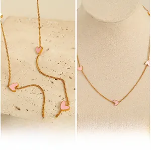 Detailed view of golden chain necklace featuring multiple pink heart enamel charms