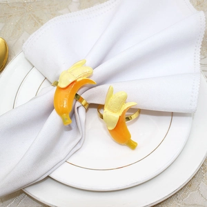 Detail of yellow banana napkin rings with gold metal bands on white table linen