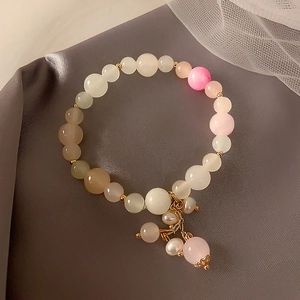 Detailed macro view of colorful strawberry crystal beaded bracelet on elegant grey satin fabric
