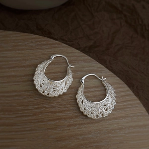Detail shot of vintage hollow filigree silver earrings with intricate lace patterns