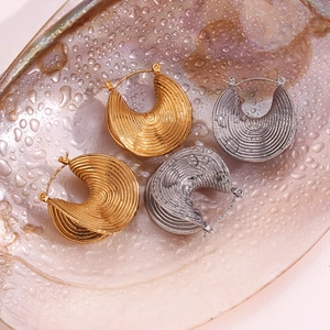 Detail of gold and silver thick ridged hoop earrings with concentric threaded texture