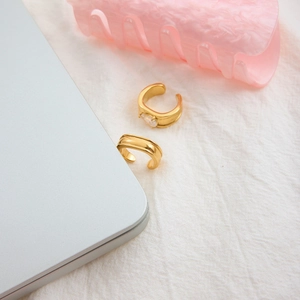 Dettaglio del set di ear cuff in zircone a goccia placcato oro 18K su tessuto