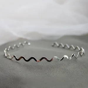 Dettaglio macro del bracciale a onde argento con finitura lucida su base in velluto