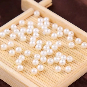 Macro shot of white round wrinkled faux pearls with drill holes on a bamboo tray
