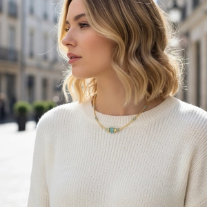 Detail of gold chain necklace with green stone beads on a model with street background