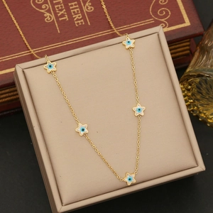 Detail of gold star necklaces with evil eye charms displayed on a beige jewelry box