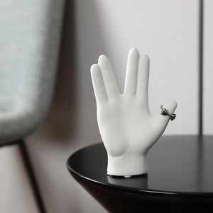 Minimalist white ceramic hand sculpture jewelry display with a metal bow ring