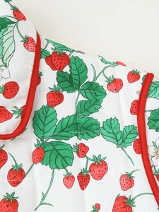 Detail of strawberry print on quilted winter jacket with red contrast piping