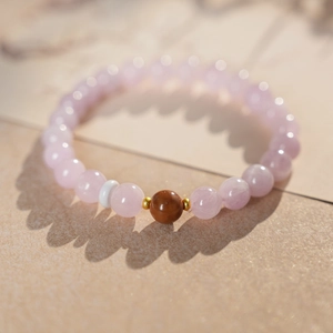 Macro detail of pink stone bead bracelet with golden spacers and decorative brown beads