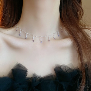 Detail of silver chain necklace with purple teardrop crystal pendants on a model's neck