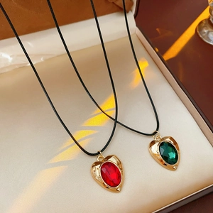 Detail of vintage gold-rimmed heart pendants with red and green gems in a jewelry box