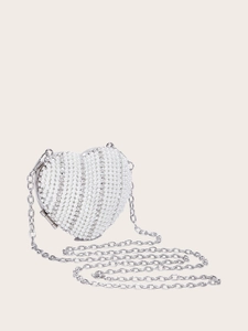 Close-up of heart-shaped evening bag with white pearls and sparkling rhinestones