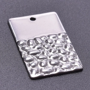 Détail macro d'un pendentif rectangulaire en acier inoxydable argenté avec texture martelée