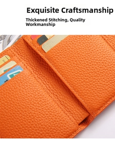 Detail view of bright orange grain leather wallet with thick stitching and card slots