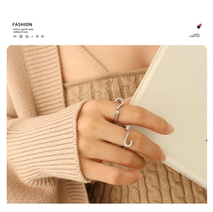 Detail of silver question mark adjustable ring on model holding book in warm light