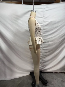 Detailed side view of beige polka dot sleeveless top with flared peplum waist hemline