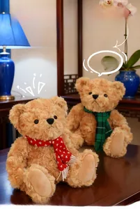 Detail of two brown teddy bears wearing red snowflake and green plaid scarves