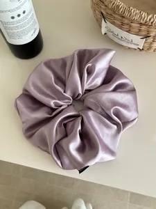 Detailed texture of a large purple satin scrunchie with soft sheen and elegant folds