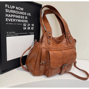 Detail view of brown vintage tote bag featuring a front buckle pocket and soft faux leather texture
