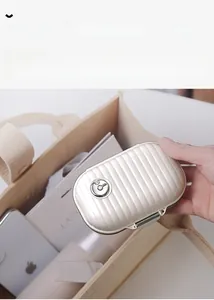 Macro view of a white suitcase-style pill box with vertical stripes and metal clasp