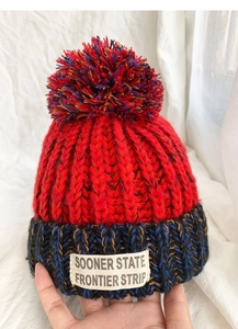 Detailed texture of kids knit hat with colorful pom-pom and vintage logo patch