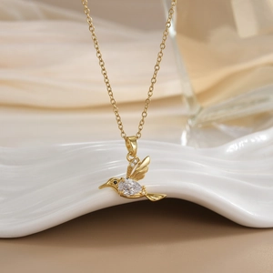 Golden hummingbird pendant necklace with sparkling cubic zirconia on white display stand