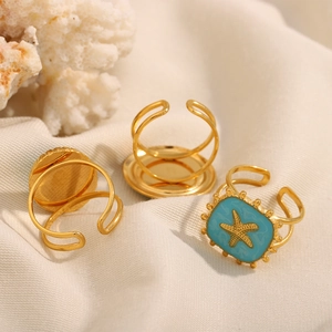 Detail of 18K gold-plated starfish ring with blue enamel inlay on a coral background