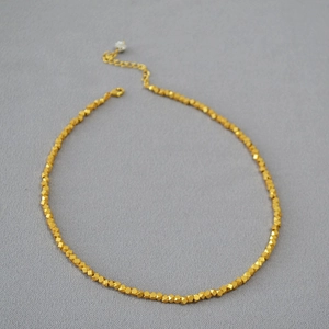 Detail of faceted gold beads on minimalist necklace with adjustable lobster clasp closure